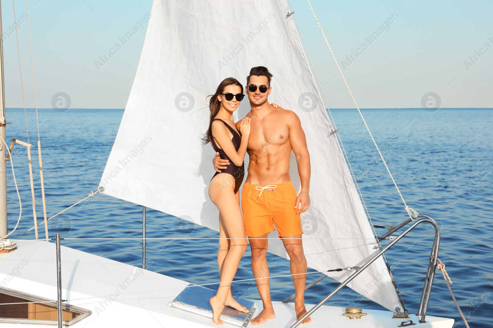 Photo of Young man and his beautiful girlfriend in bikini on yacht. Happy couple during sea trip