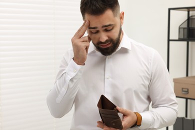 Photo of Upset man with empty wallet in office