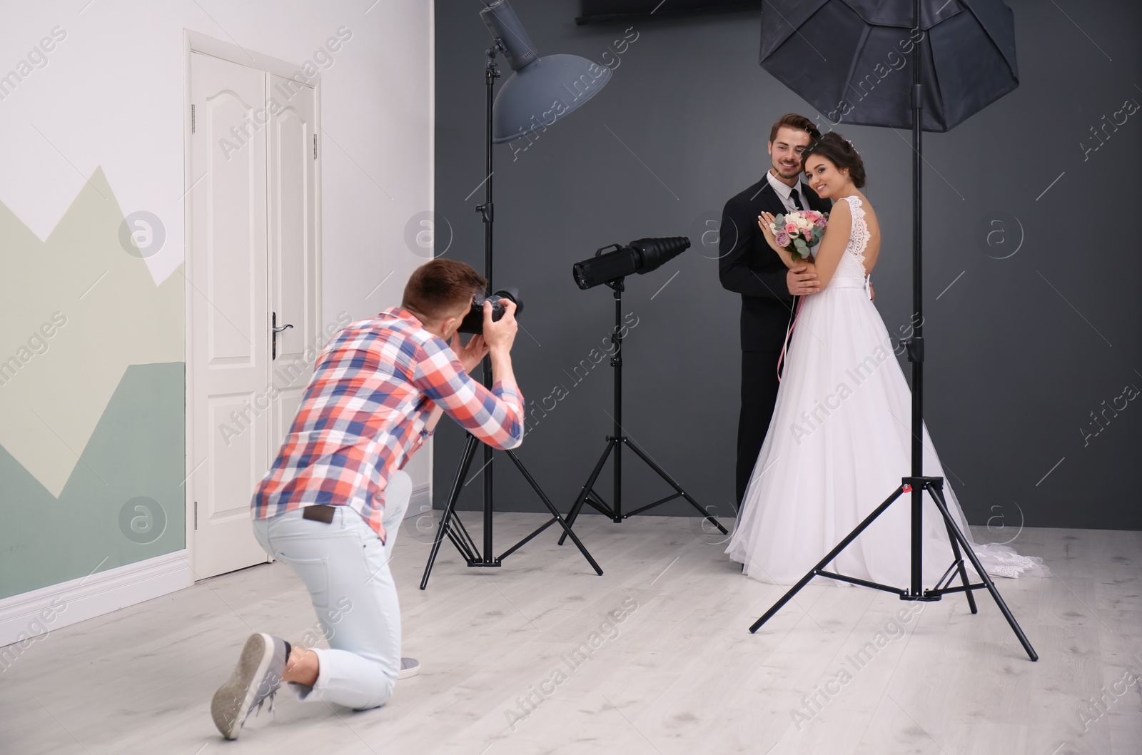 Photo of Professional photographer taking photo of wedding couple in studio