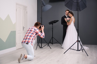 Professional photographer taking photo of wedding couple in studio