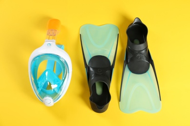 Swimming flippers and mask on color background, top view