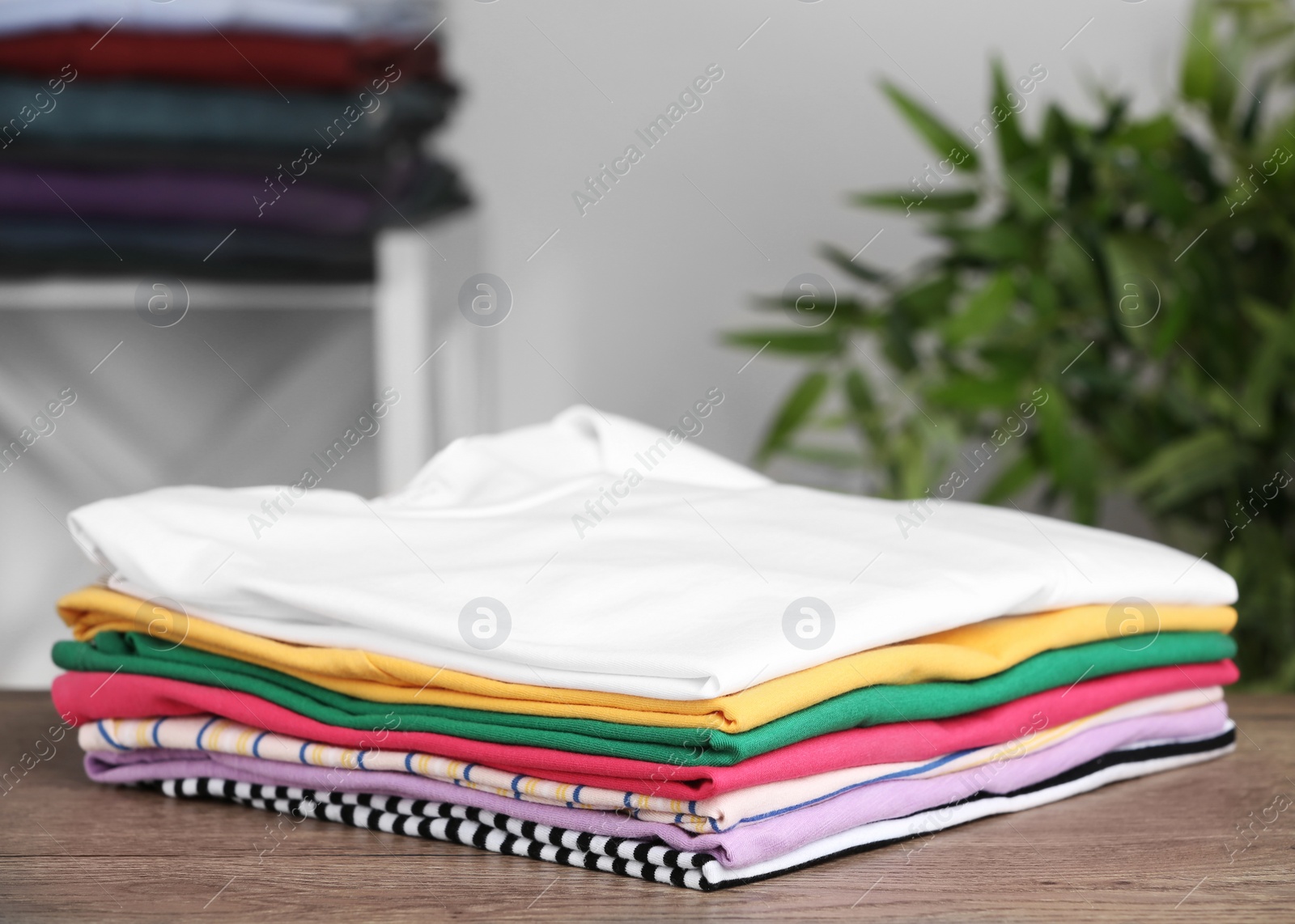 Photo of Pile of ironed clothes on table in room