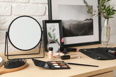 Mirror and makeup products on wooden dressing table, closeup