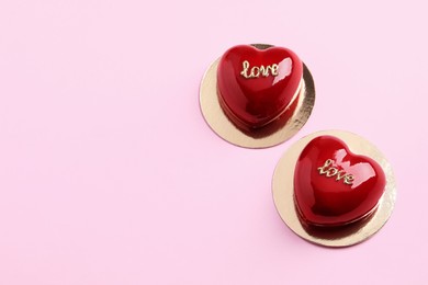 Photo of St. Valentine's Day. Delicious heart shaped cakes on light pink background, above view. Space for text