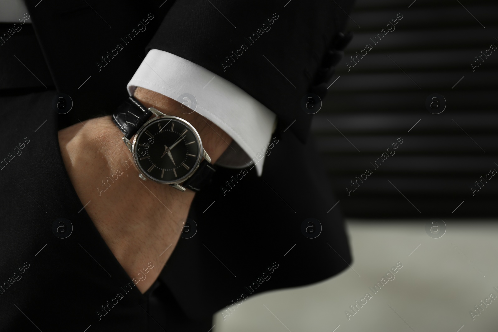 Photo of Businessman with luxury wrist watch on blurred background, closeup