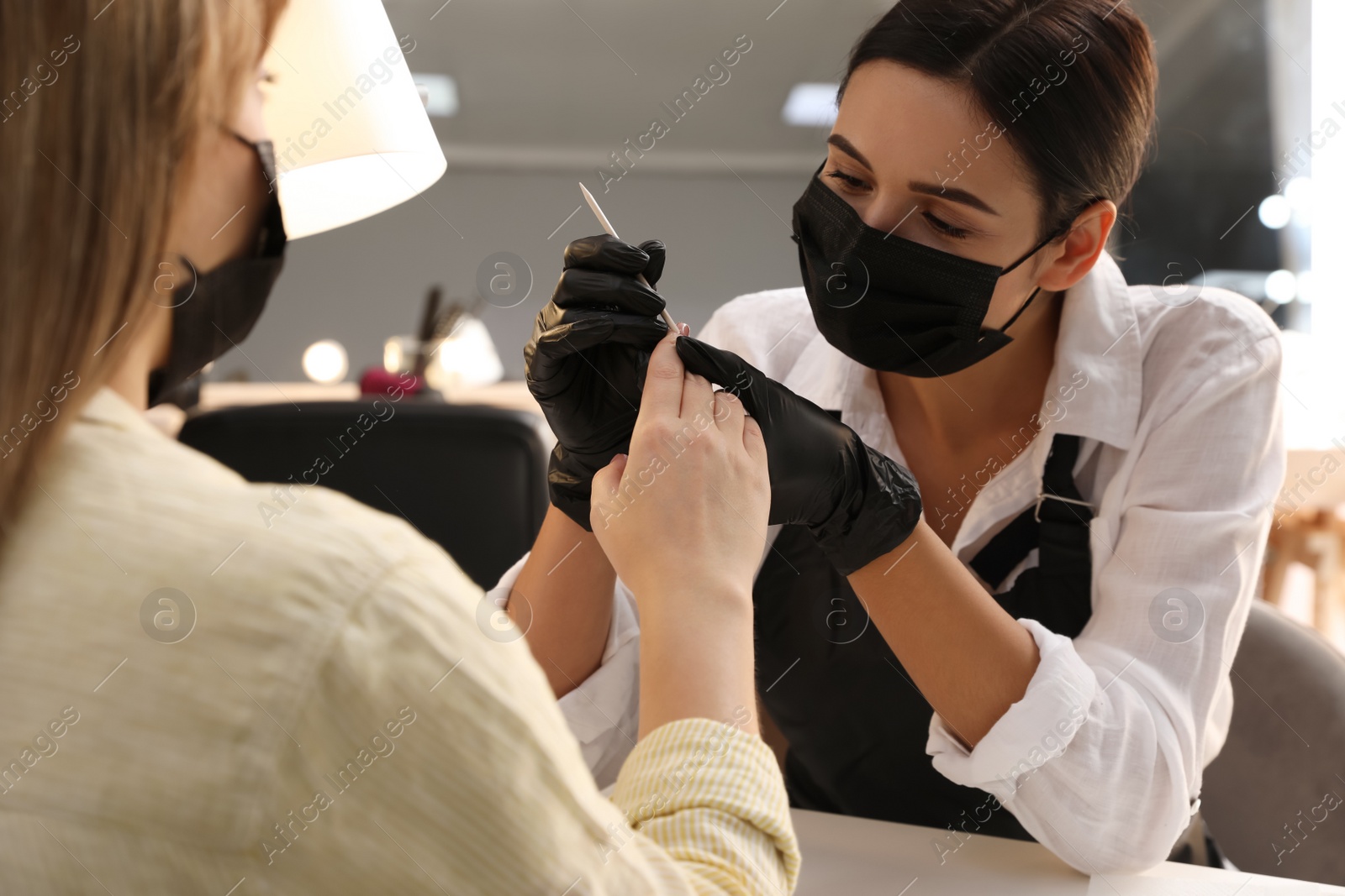 Photo of Professional manicurist working with client in salon, closeup. Beauty services during Coronavirus quarantine