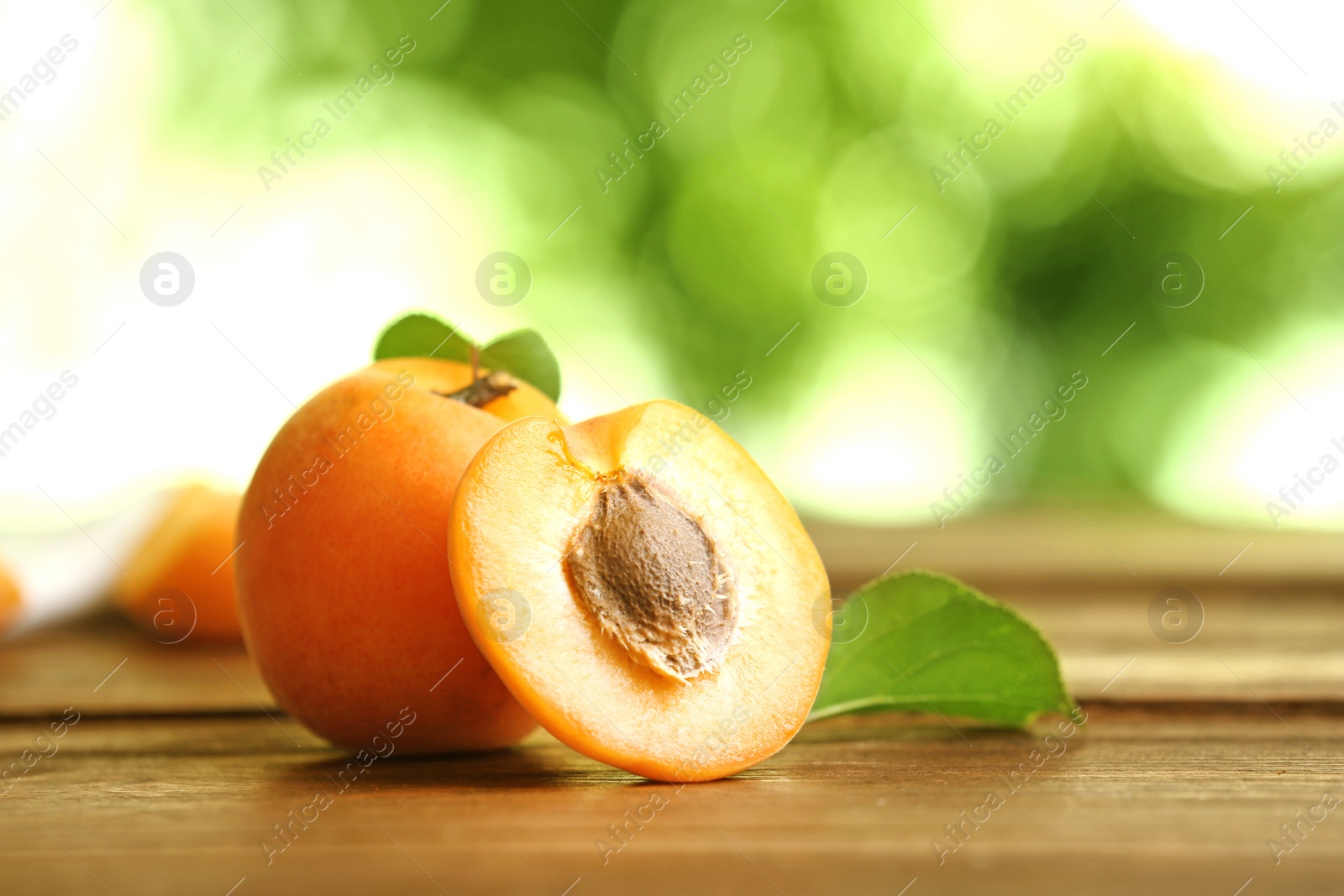 Photo of Delicious ripe sweet apricots on wooden table against blurred background, closeup view. Space for text