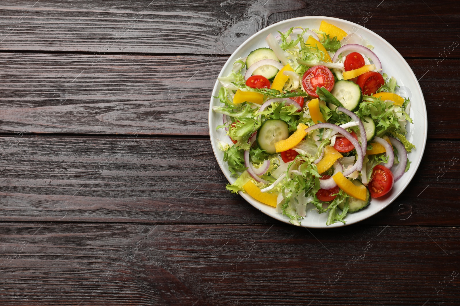 Photo of Tasty fresh vegetarian salad on dark wooden table, top view. Space for text