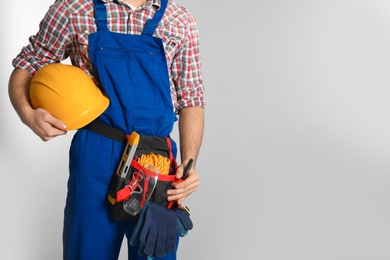 Photo of Construction worker with tool belt on light background, closeup. Space for text