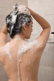 Woman washing hair in shower, back view