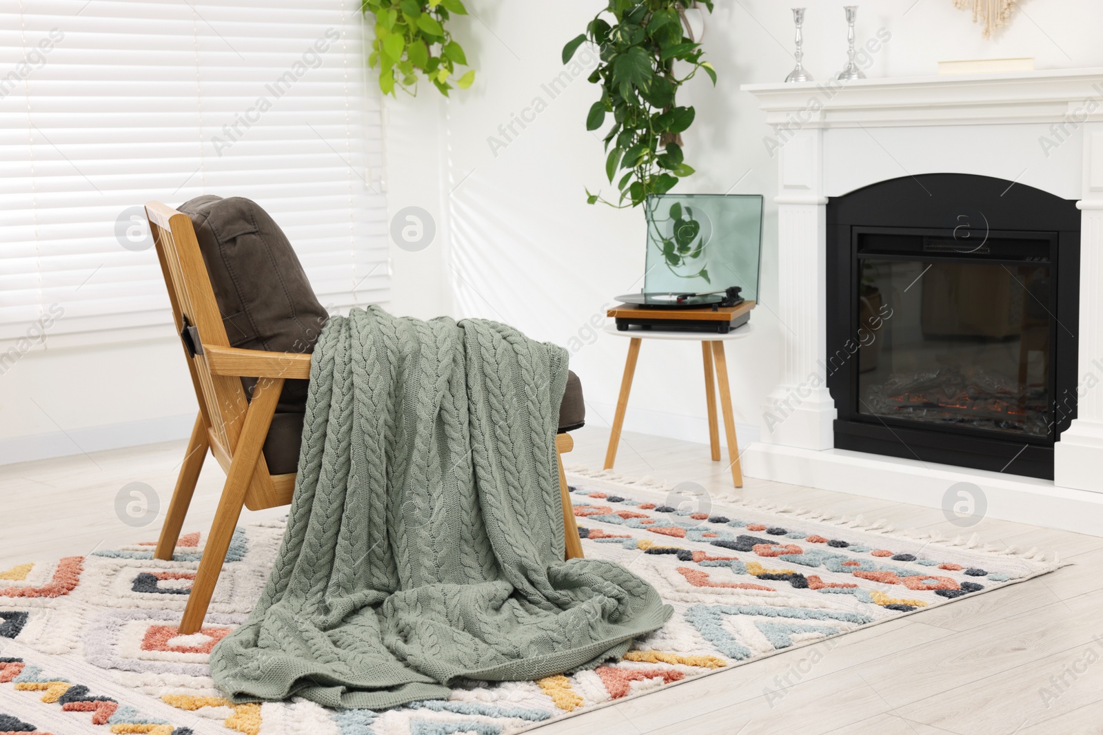 Photo of Stylish living room interior with comfortable armchair, blanket and fireplace