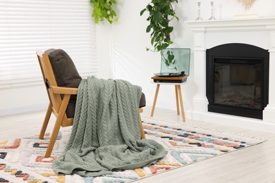 Stylish living room interior with comfortable armchair, blanket and fireplace