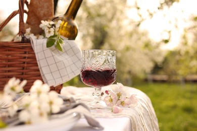 Photo of Stylish table setting with beautiful spring flowers and wine in garden
