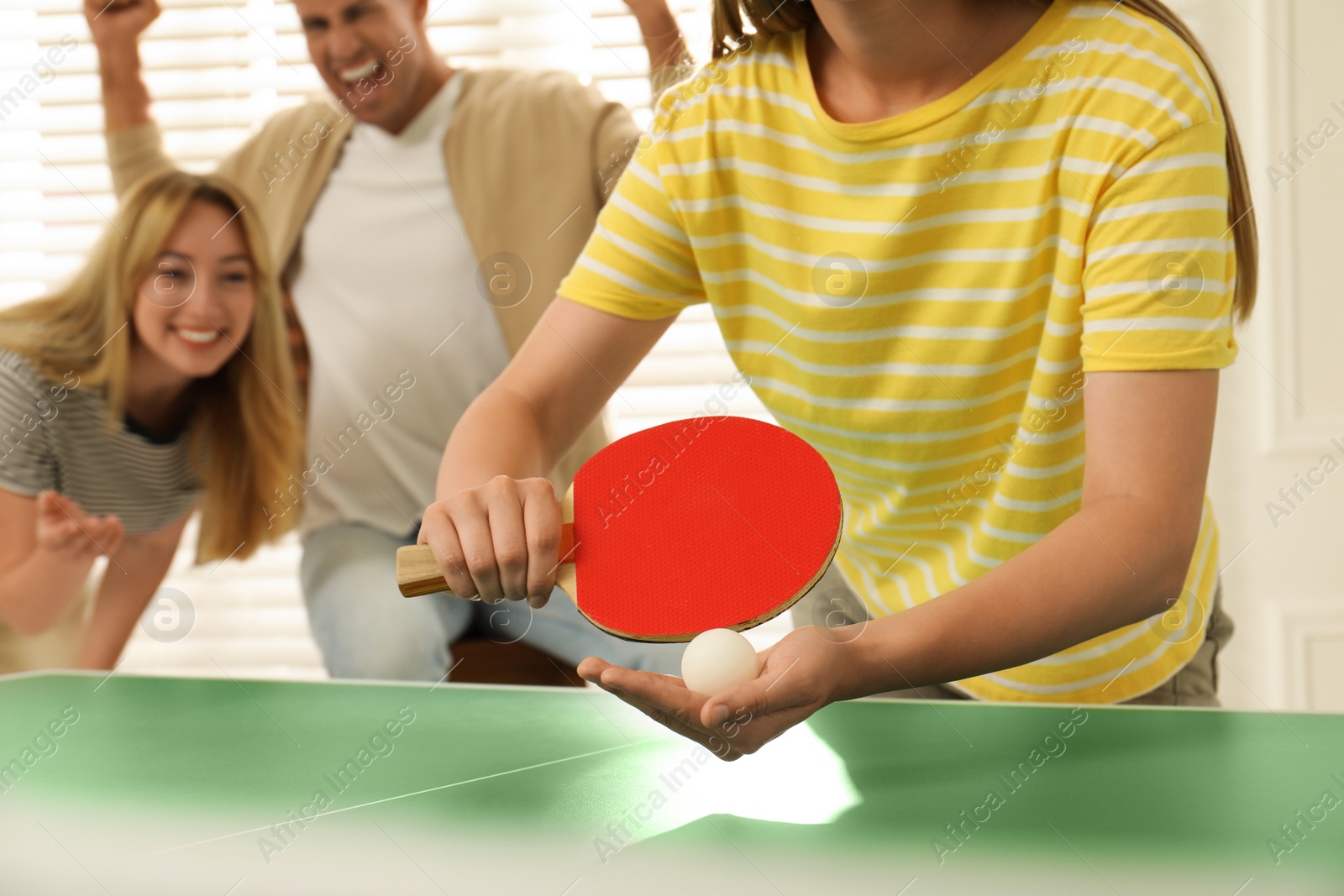 Photo of Woman playing ping pong with friends indoors, closeup