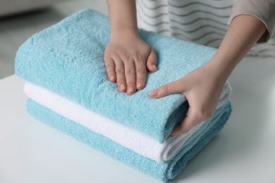 Photo of Woman touching soft light blue towel indoors, closeup