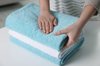 Woman touching soft light blue towel indoors, closeup