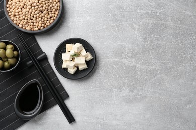 Pieces of delicious tofu, olives and soy on grey table, flat lay. Space for text