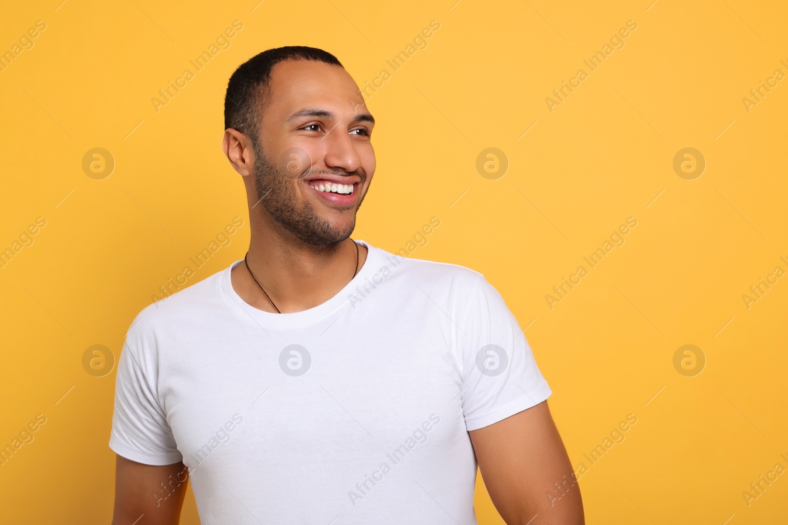 Photo of Portrait of happy African American man on orange background. Space for text