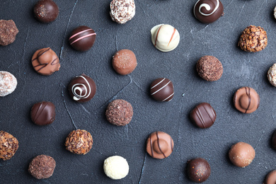 Photo of Different tasty chocolate candies on black table, flat lay