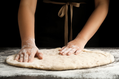 Photo of Woman kneading dough for pizza at grey table, closeup