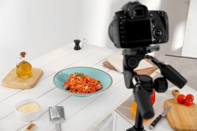 Photo of Professional camera and composition with delicious spaghetti on table in photo studio. Food photography