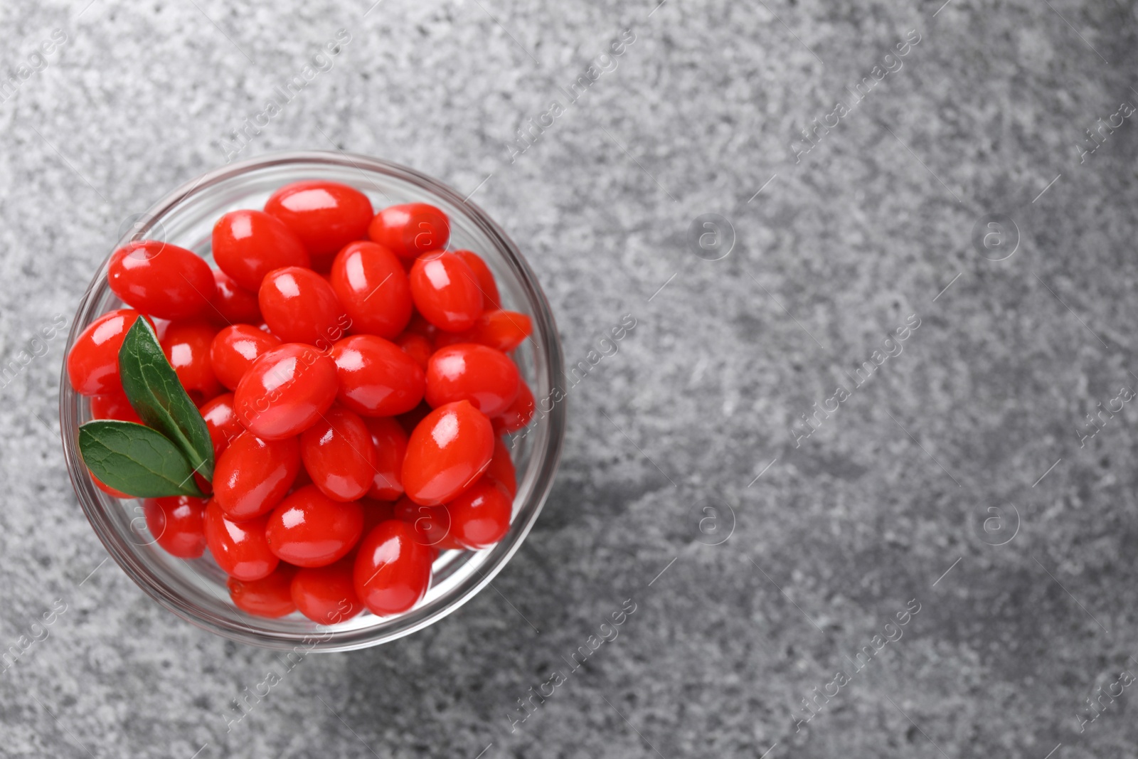 Photo of Bowl with fresh goji berries on grey background, top view. Space for text