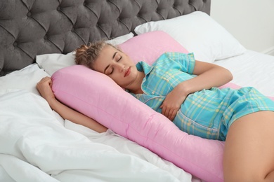 Photo of Beautiful pregnant woman sleeping with maternity pillow on bed at home