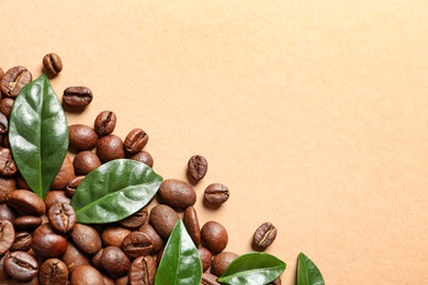 Photo of Fresh green coffee leaves and beans on light orange background, flat lay. Space for text