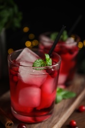 Tasty refreshing cranberry cocktail with mint on wooden table