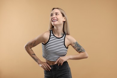 Portrait of beautiful tattooed woman on beige background