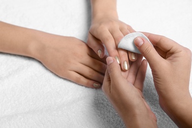 Photo of Manicurist removing polish from client's nails on white fabric, closeup