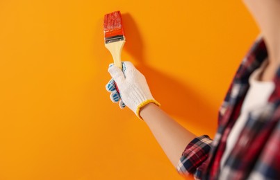 Designer painting orange wall with brush, closeup