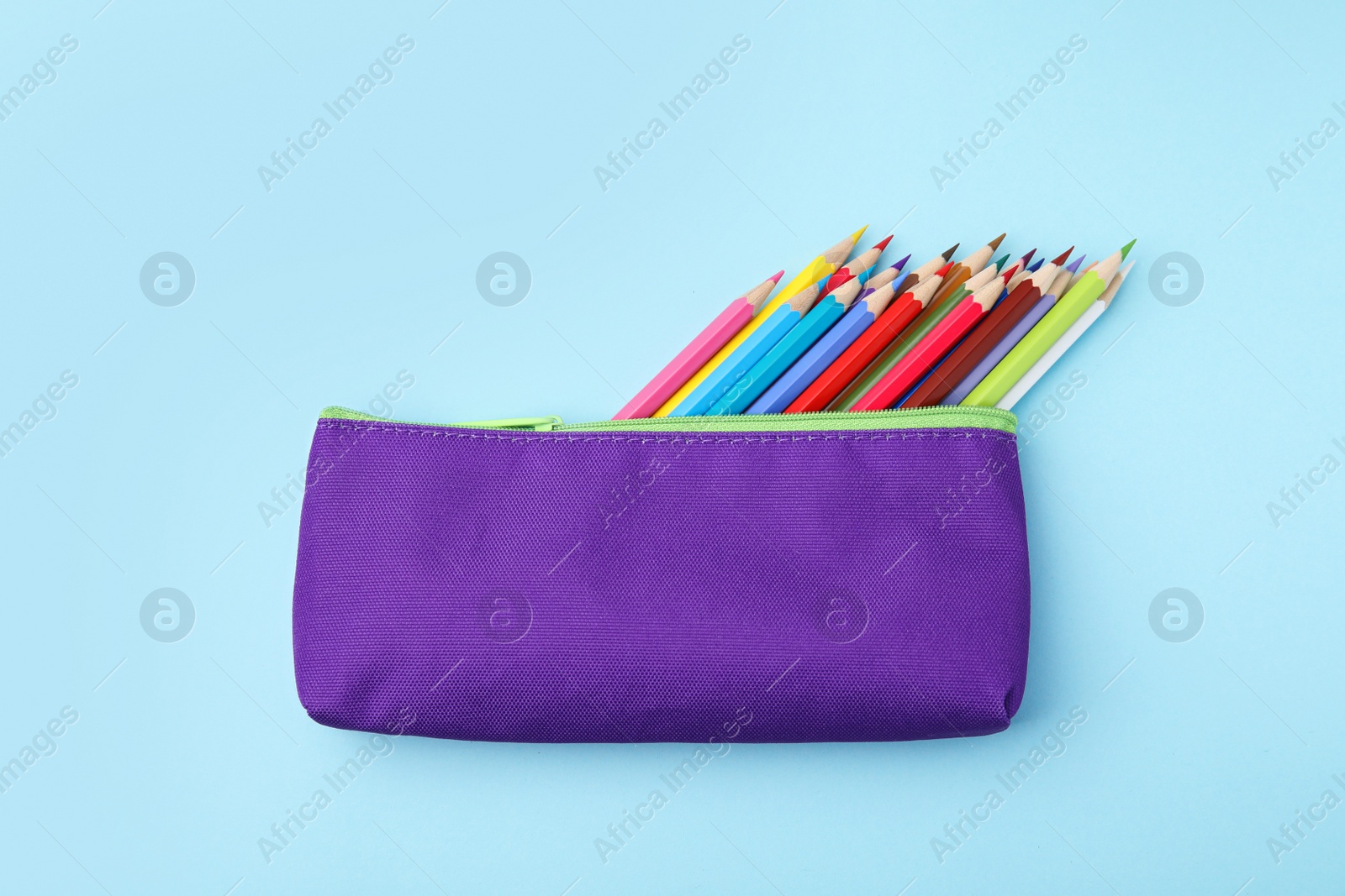 Photo of Many colorful pencils in pencil case on light blue background, top view