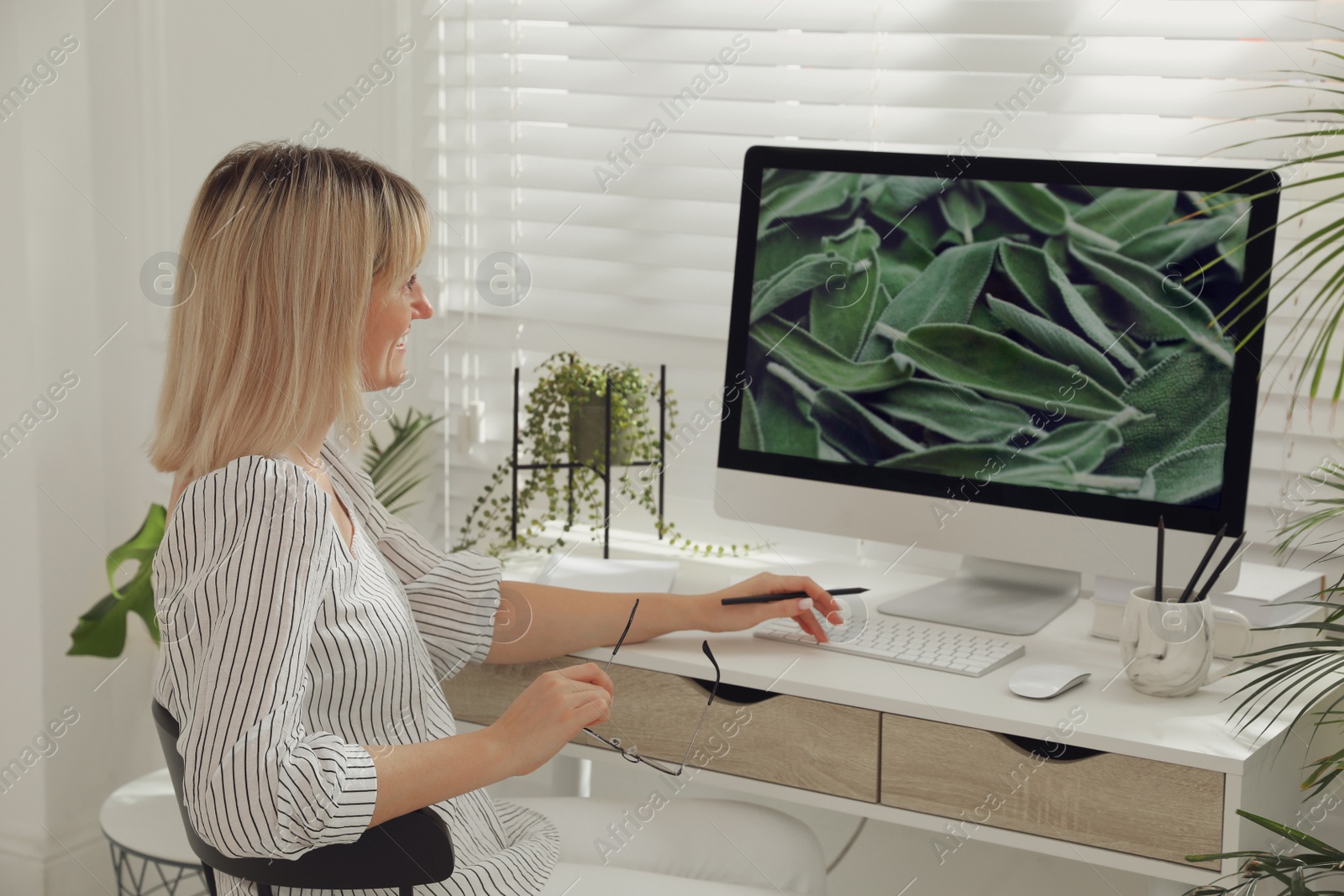 Photo of Woman working on computer at table in room. Interior design