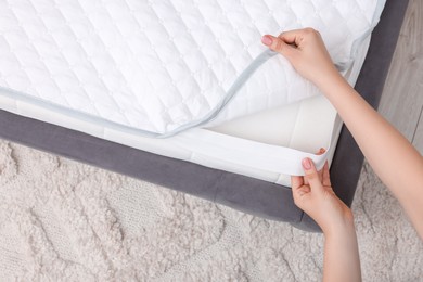 Photo of Woman putting cover on mattress indoors, top view