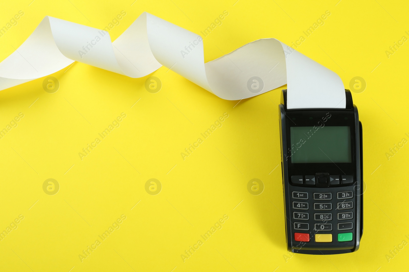 Photo of New modern payment terminal with blank paper bill on yellow background, top view. Space for text