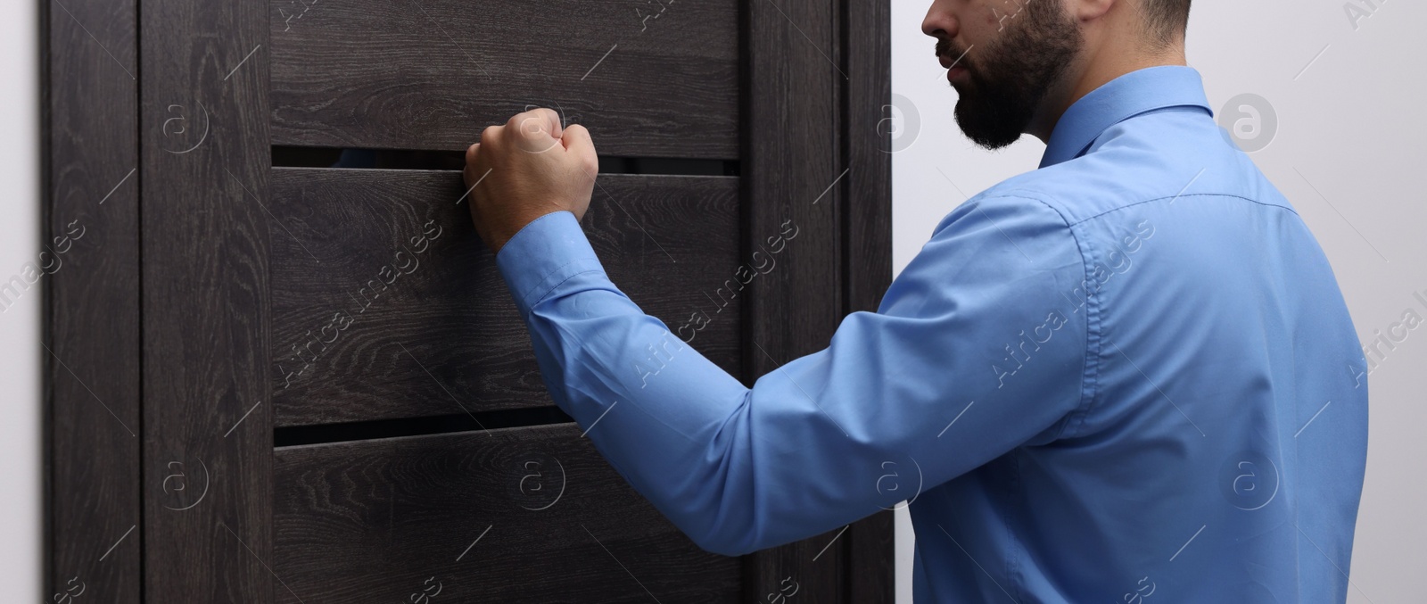 Photo of Collection agent knocking on wooden door, closeup