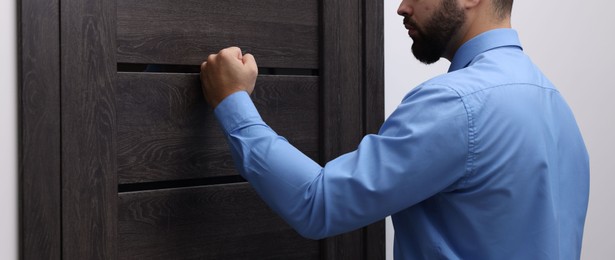 Photo of Collection agent knocking on wooden door, closeup