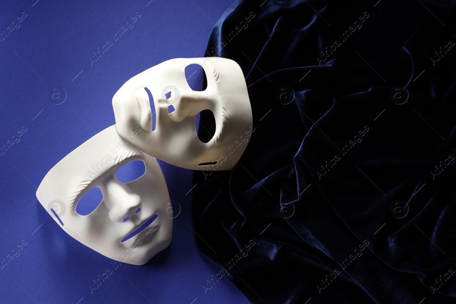 Photo of Theater arts. White masks and fabric on blue background, top view