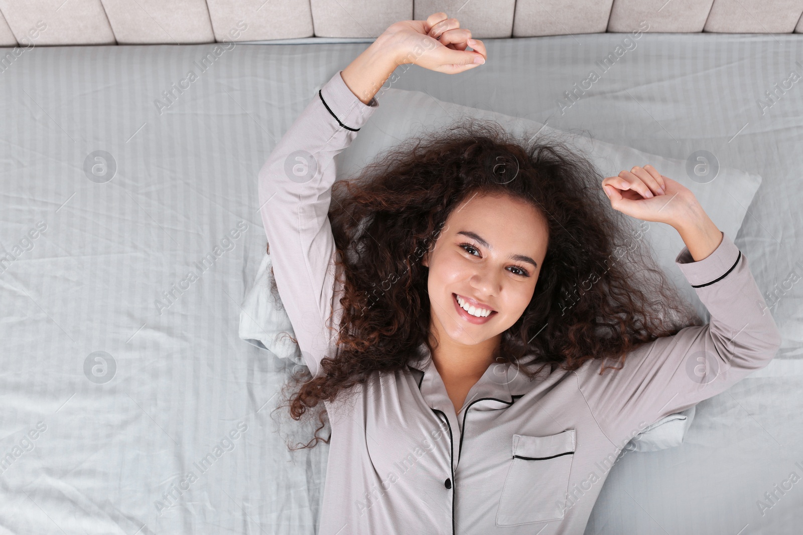 Photo of Beautiful African American woman lying in bed, top view