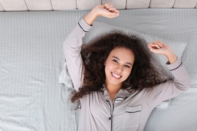 Photo of Beautiful African American woman lying in bed, top view