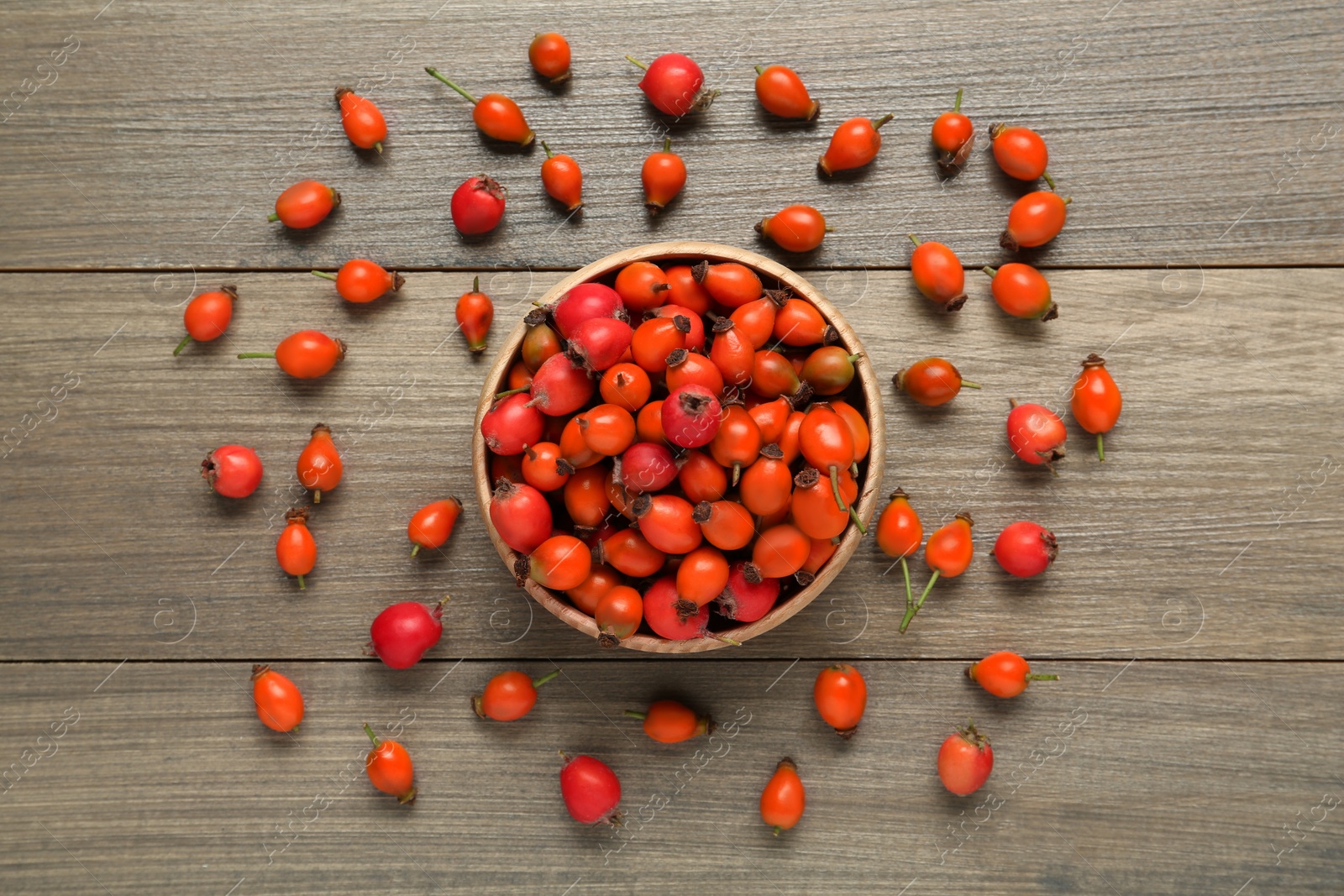 Photo of Ripe rose hip berries on wooden table, flat lay