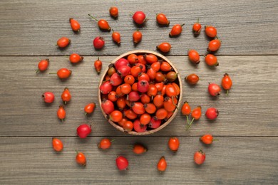 Ripe rose hip berries on wooden table, flat lay