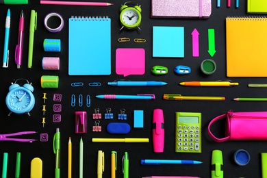 Photo of Different bright school stationery on black background, flat lay