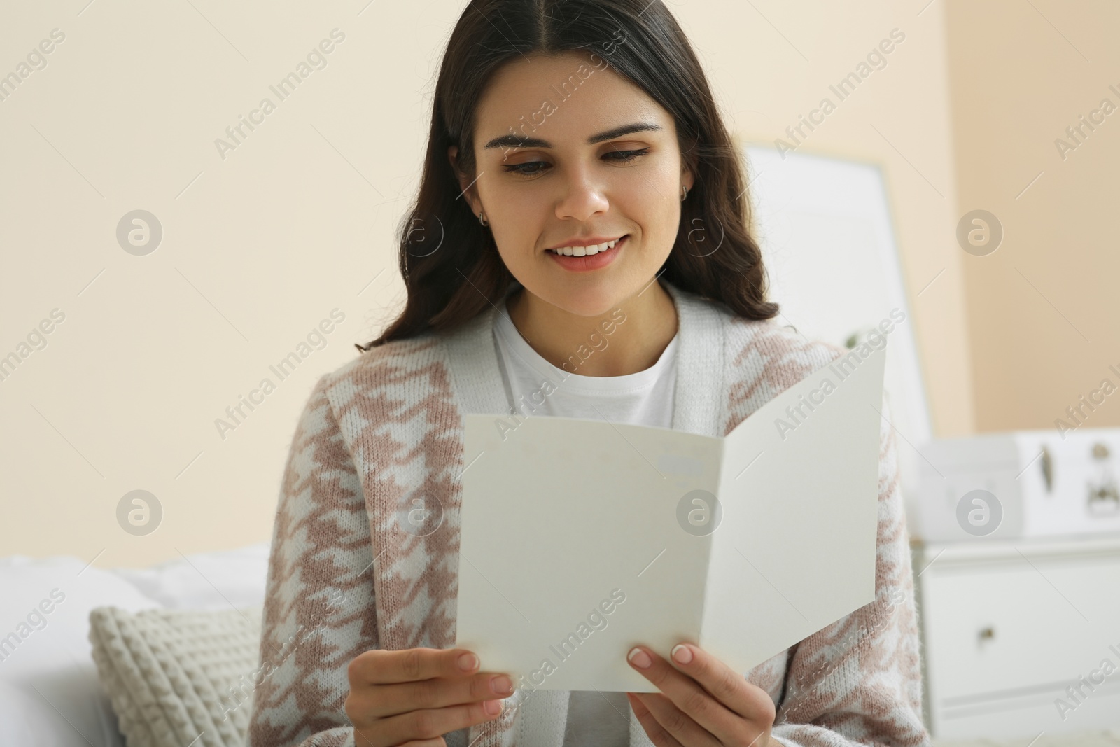 Photo of Young woman with greeting card in bedroom