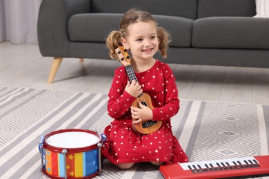 Photo of Little girl playing toy guitar at home