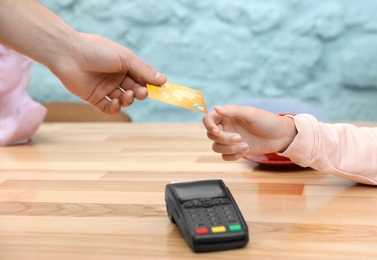 Client using credit card machine for non cash payment at table, closeup