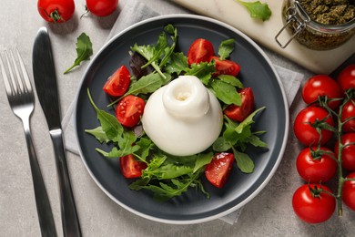 Photo of Delicious burrata salad with tomatoes and arugula served on grey table, flat lay