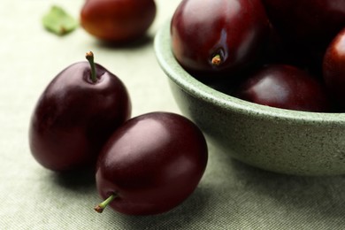 Photo of Many tasty ripe plums on light fabric, closeup