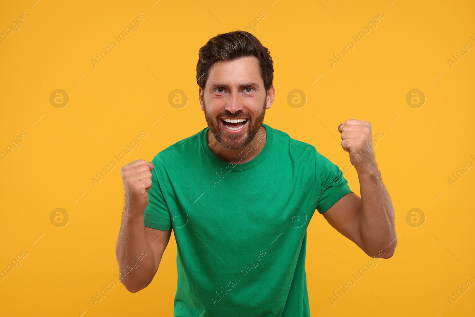 Photo of Emotional sports fan celebrating on orange background